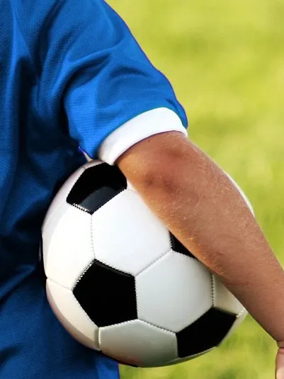 Barn i fotbollströja med en fotboll